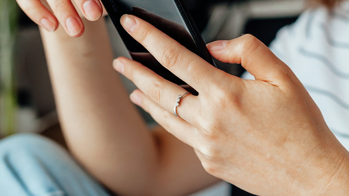 Gros plan sur les mains d'une personne tenant un smartphone noir, lumière naturelle