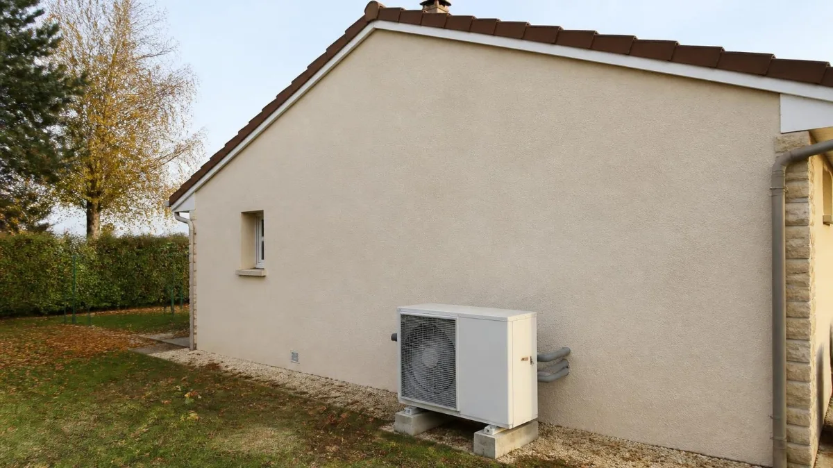 Unité extérieure de pompe à chaleur air-eau installée contre la façade d'une maison isolée par l'extérieur