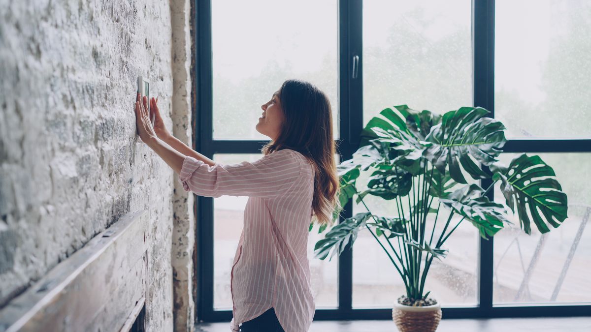 Personne réglant le thermostat mural de son logement avant l'hiver
